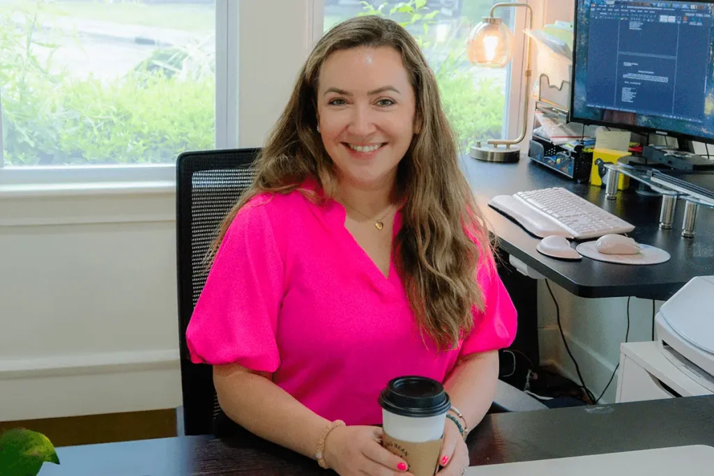 Jennifer Strang smiling with a cup of coffee in her office at Strang Immigration