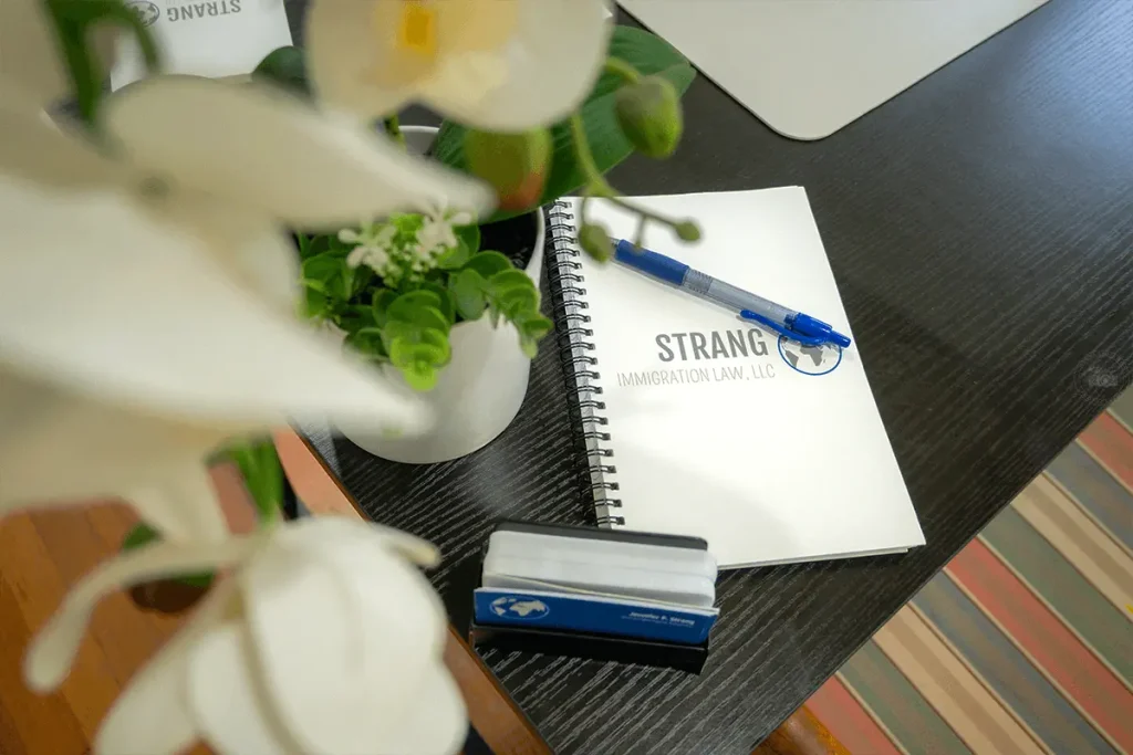 Strang Immigration branded pen and paper used for visa application preparation