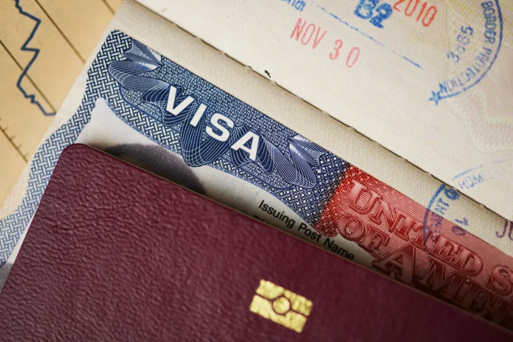 Close-up view of a U.S. visa inside a passport with immigration documents in the background.