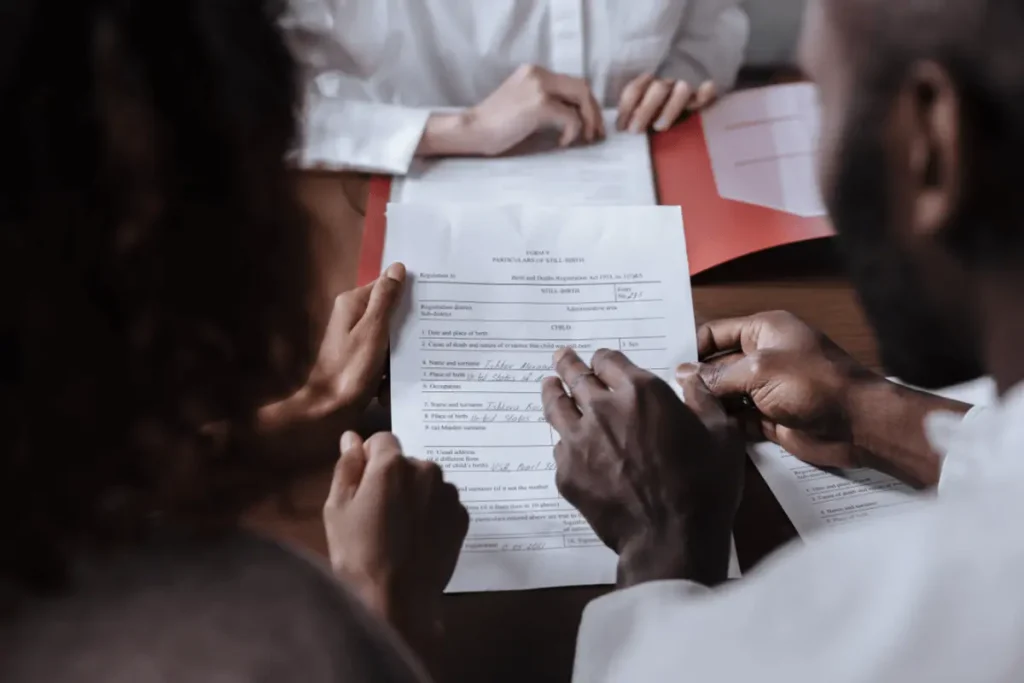 Close-up of a couple reviewing immigration paperwork together at a desk, focusing on the documents in their hands.
