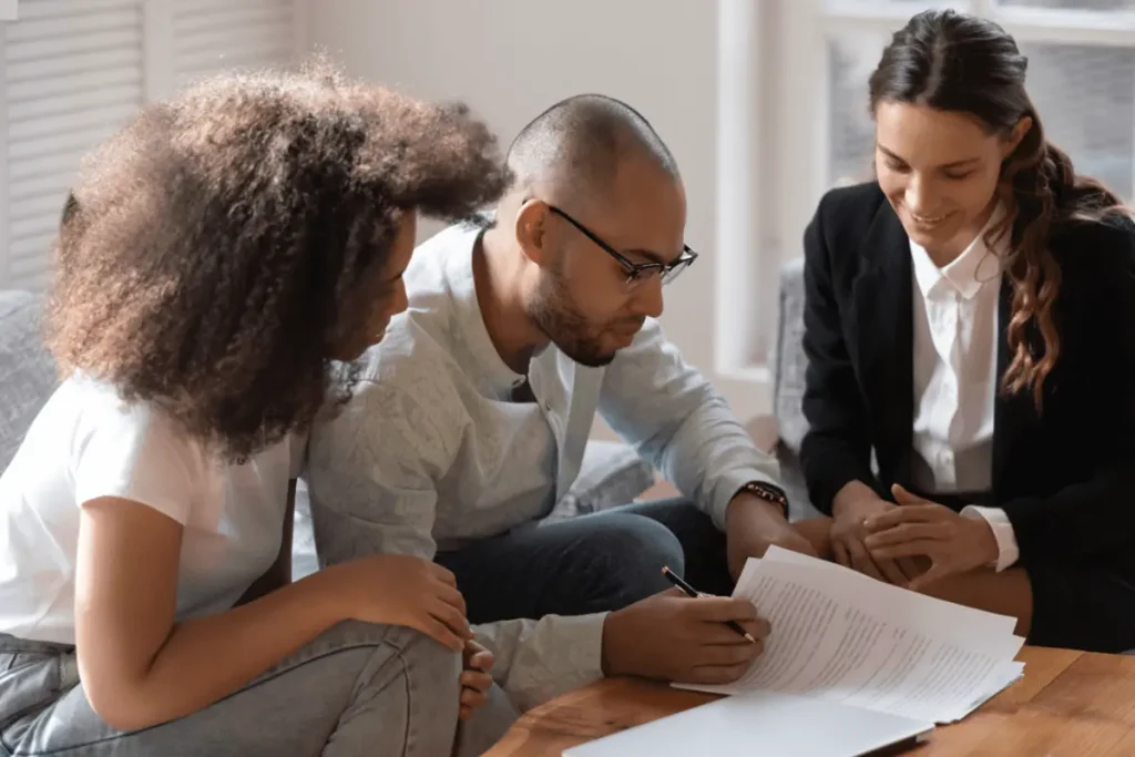 Close-up of a couple holding and reviewing immigration documents while sitting with a legal advisor at a desk.