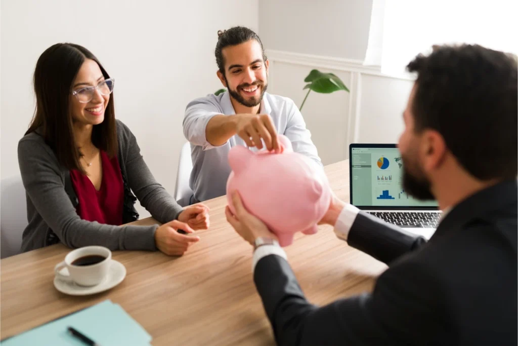 Young couple meeting with financial advisor discussing savings with piggy bank and laptop