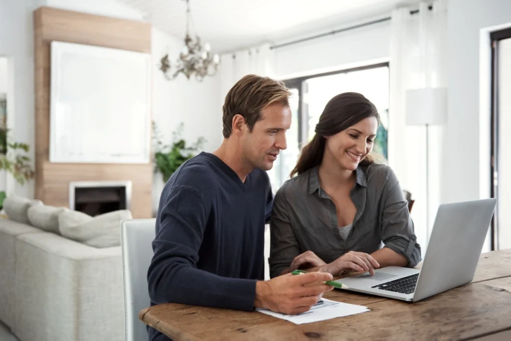 Man and woman using laptop computer together filling out forms at home