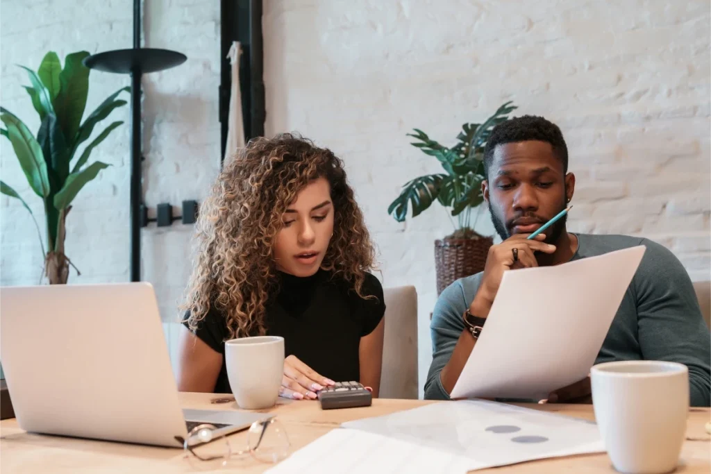 Man and woman analyzing paperwork and using calculator for financial planning together