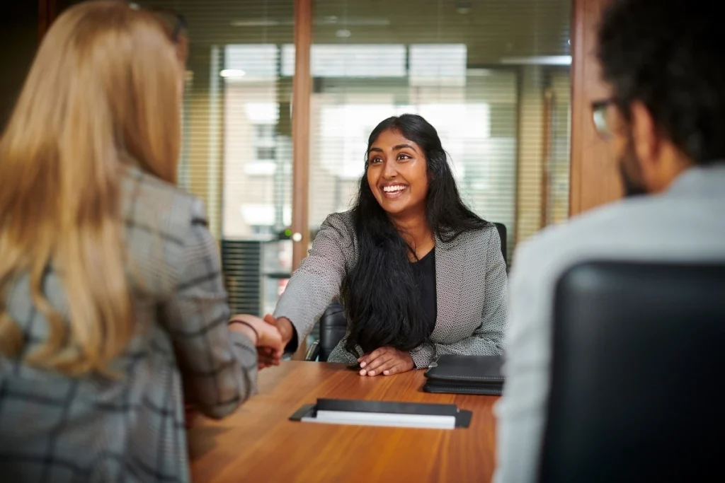 Smiling woman shaking hands with immigration officials during successful visa interview