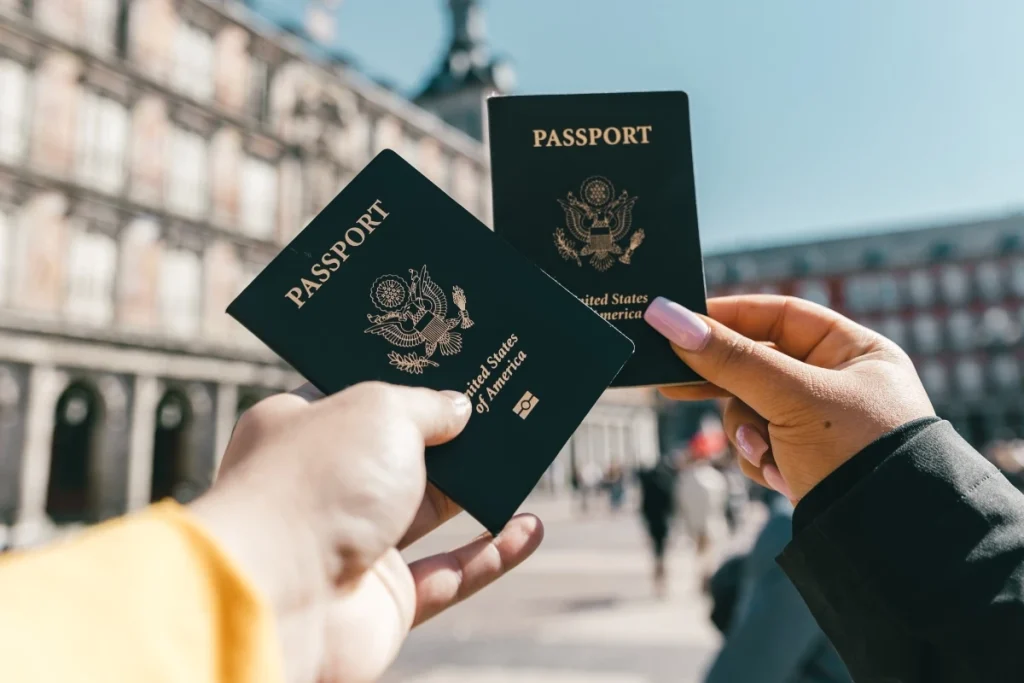 Hands holding two United States passports outdoors in urban city setting