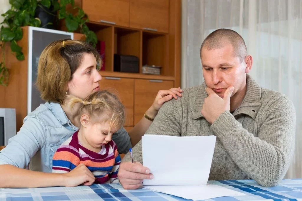 Concerned parents review immigration paperwork at home while their young child sits beside them—reflecting the challenges and hope for relief under the American Families United Act.