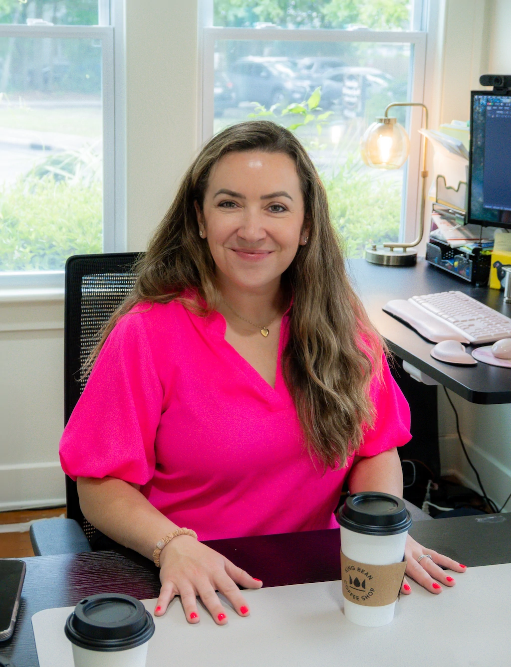 Jennifer Strang smiling with a cup of coffee in her office at Strang Immigration